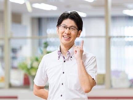 笑顔で指をさす白いシャツの男性