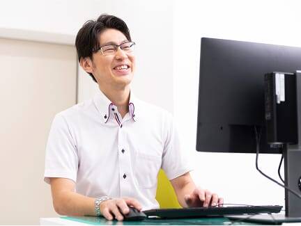 パソコンを操作しながら笑顔を見せる男性スタッフ